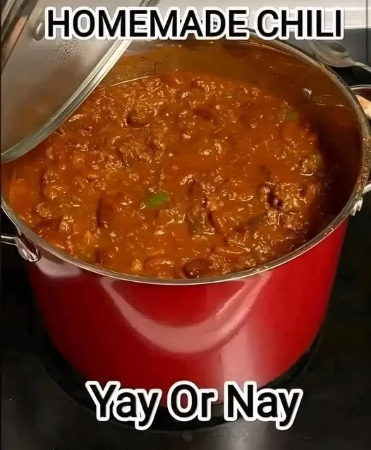A bowl of hearty chili topped with cilantro and sour cream, served with bread.