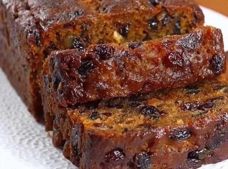 Delicious mixed dried fruit loaf with nuts and spices on a wooden table.