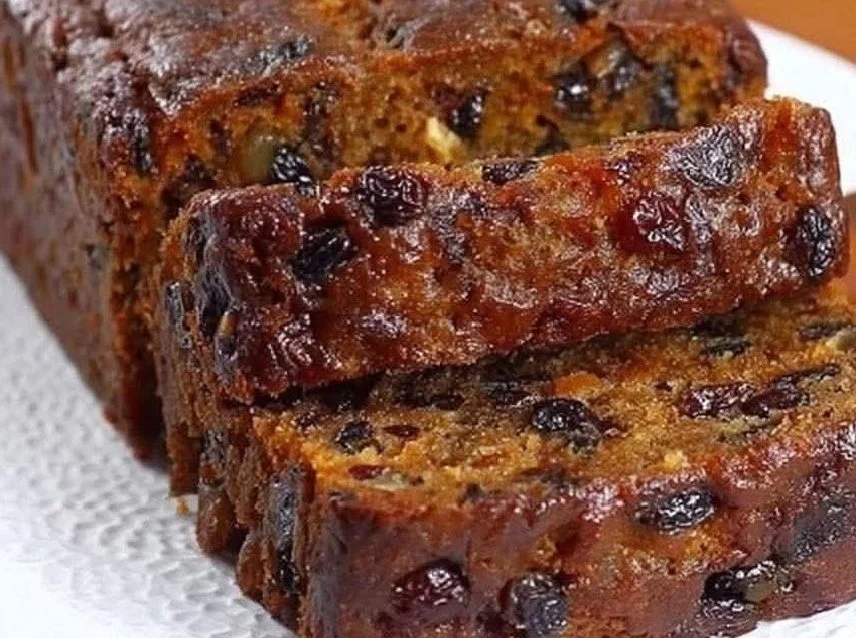 Delicious mixed dried fruit loaf with nuts and spices on a wooden table.